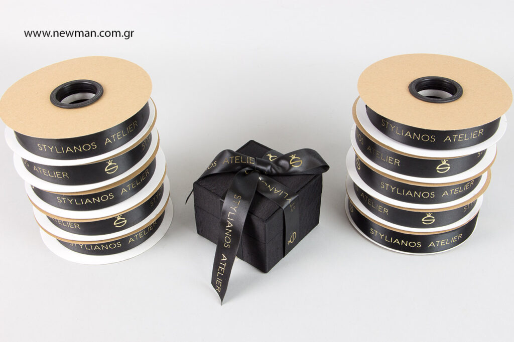 Η Newman Packaging Company τύπωσε σατέν κορδέλες διπλής όψης φάρδους 25x50 με τη μέθοδο της θερμοτυπίας σε χρυσό χρώμα για το «STYLIANOS ATELIER». 