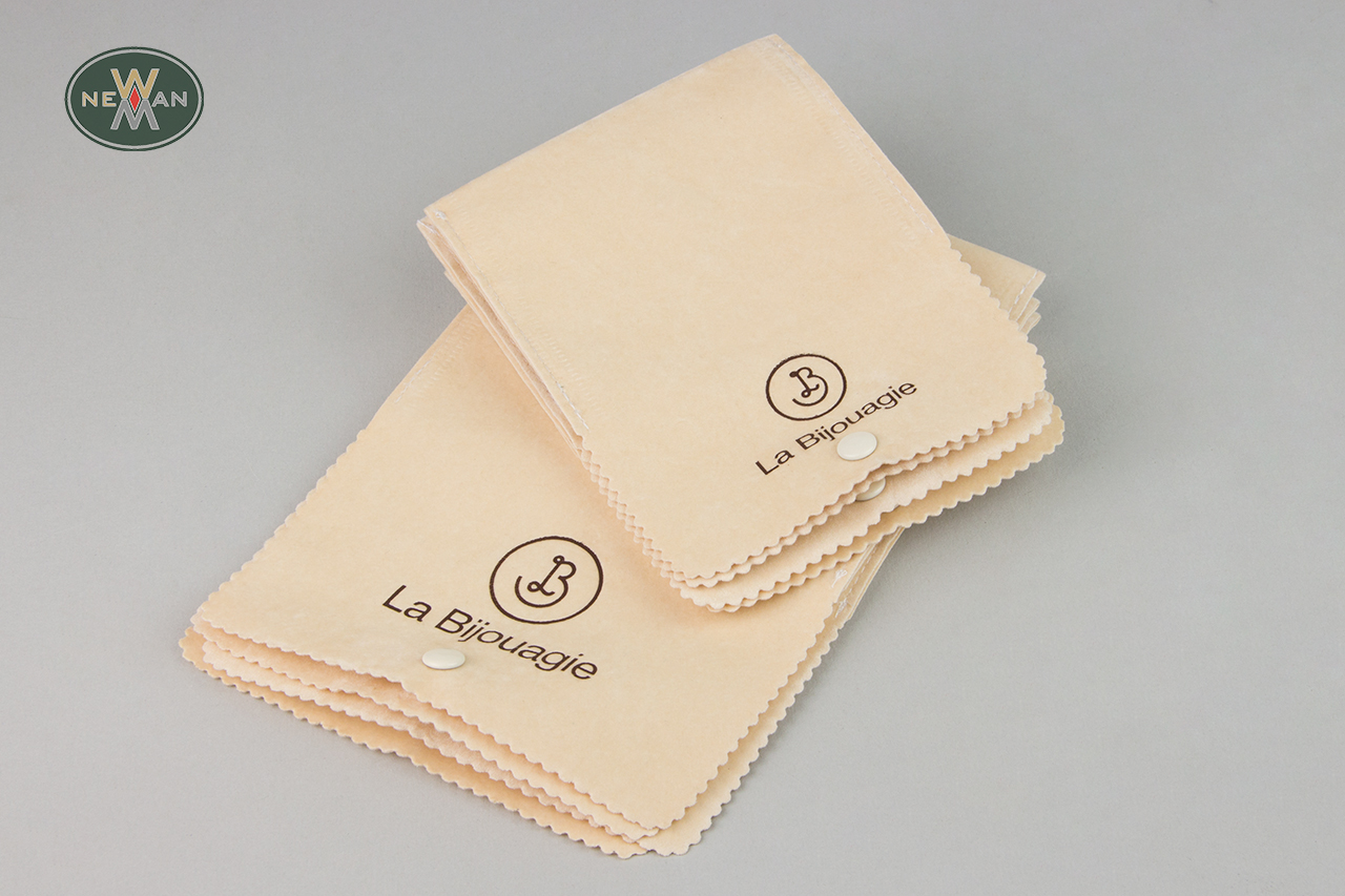 Off-white suede pouches with matching push-button and brown logo.